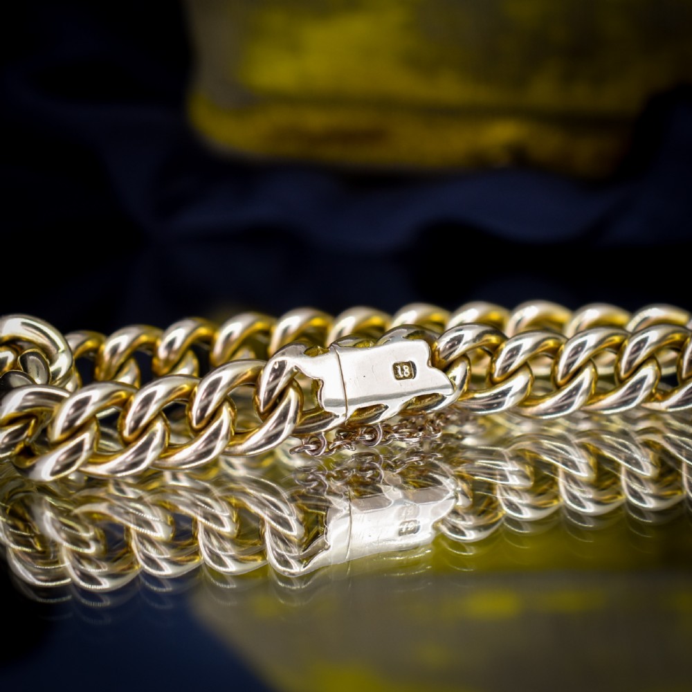 An 18ct yellow gold curb link bracelet featuring a concealed box clasp and an attached safety chain. View V