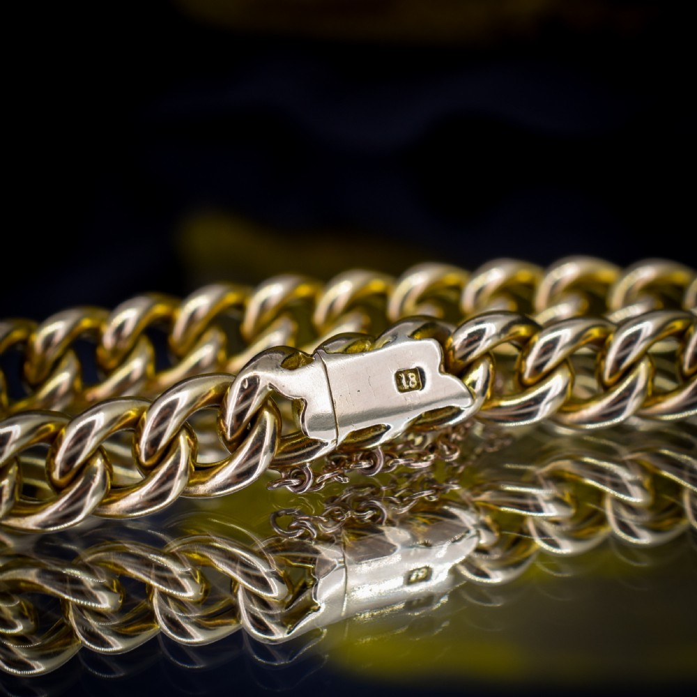 An 18ct yellow gold curb link bracelet featuring a concealed box clasp and an attached safety chain. View VI