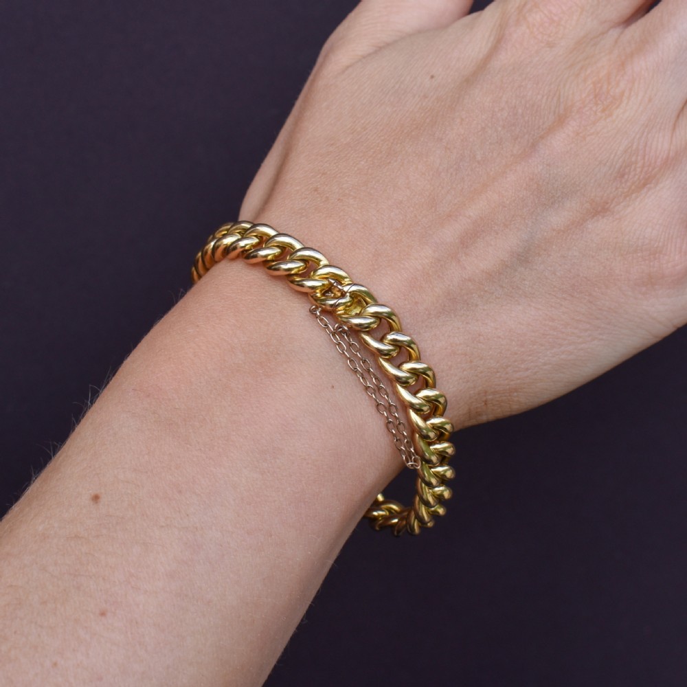 An 18ct yellow gold curb link bracelet featuring a concealed box clasp and an attached safety chain. View VIII