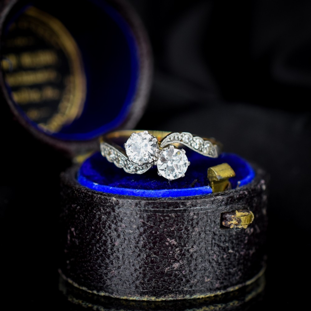 An antique diamond Toi et Moi ring featuring two diamonds set in a platinum crossover mount on an eighteen carat gold band.
