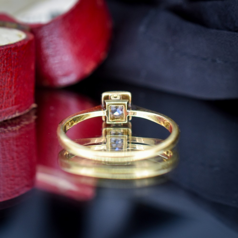 An antique 18ct yellow gold solitaire ring holding a central round old cut diamond within a square white metal setting. View VI