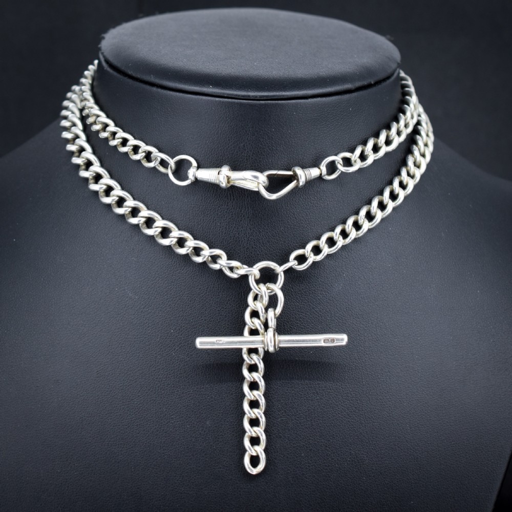 A sterling silver curb link Albert watch chain necklace featuring a central T-bar attachment and swivel clasp on a black bust.