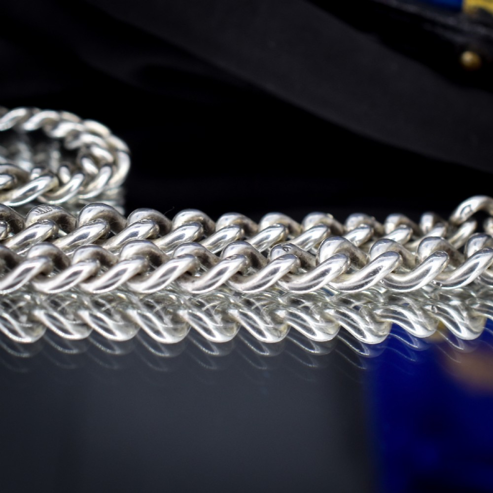 A sterling silver curb link Albert watch chain necklace featuring a central T-bar attachment and swivel clasp on a black bust. View V