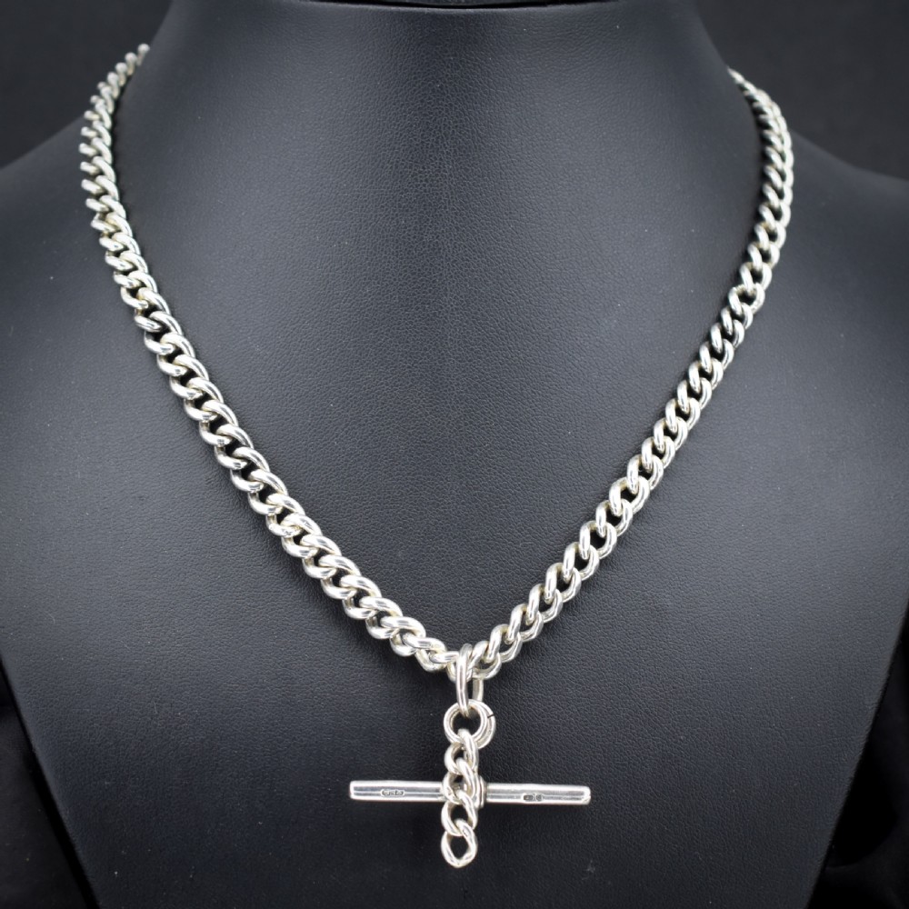 A sterling silver uniform curb link necklace with a T-bar pendant and dog clip clasp displayed on a black neck bust.