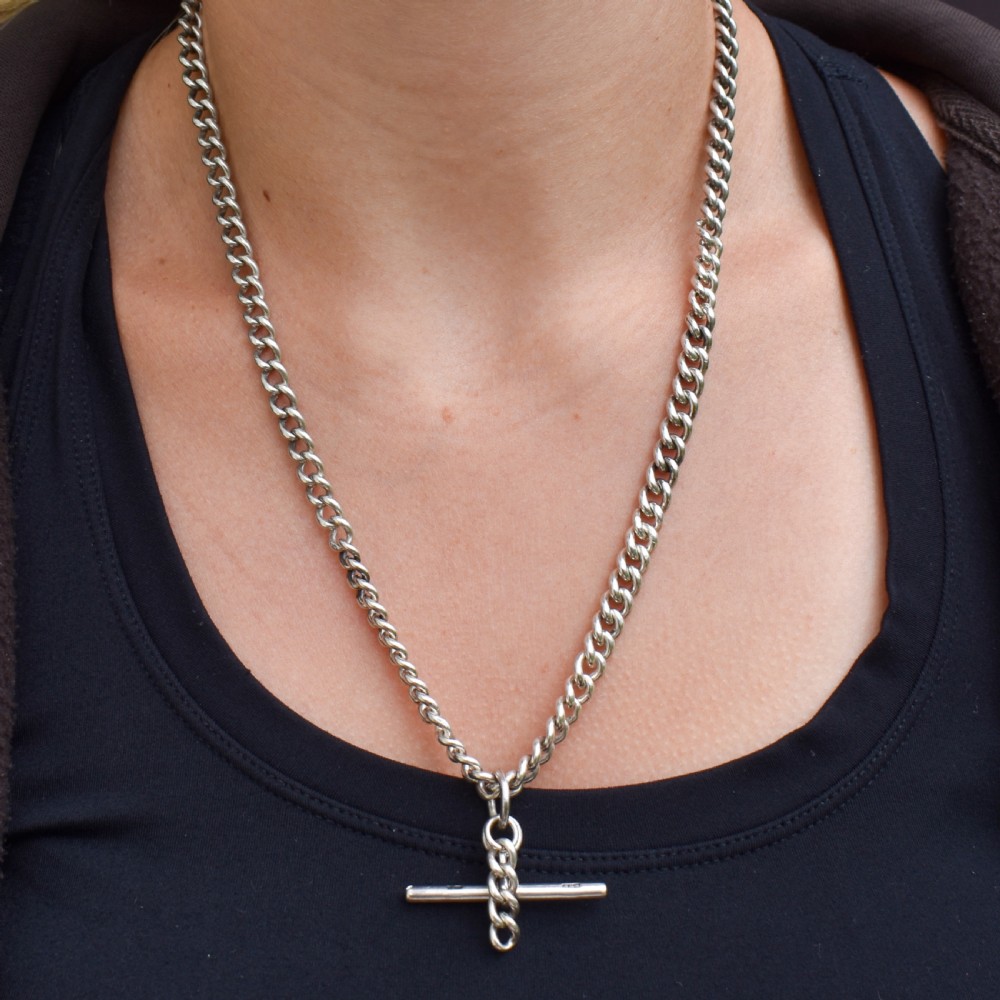 A sterling silver uniform curb link necklace with a T-bar pendant and dog clip clasp displayed on a black neck bust. View VIII