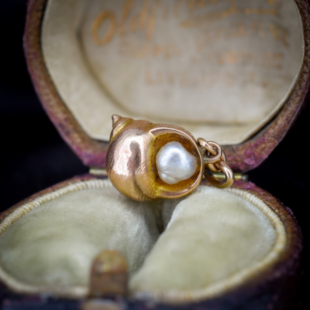 A 9ct yellow gold seashell charm enclosing a single pearl with a top suspension loop. View II