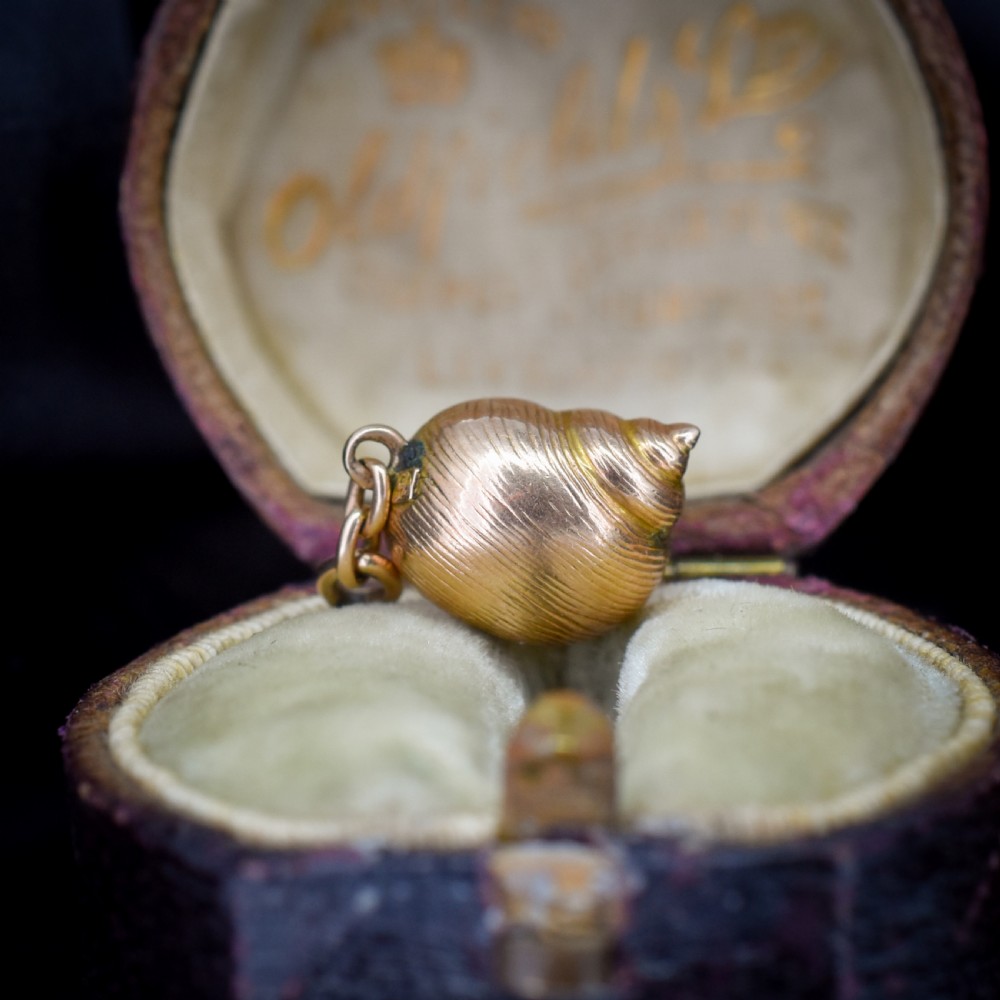 A 9ct yellow gold seashell charm enclosing a single pearl with a top suspension loop. View III