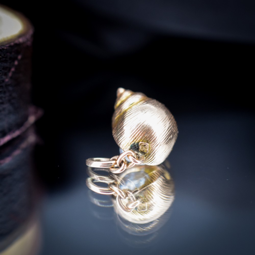 A 9ct yellow gold seashell charm enclosing a single pearl with a top suspension loop. View IV