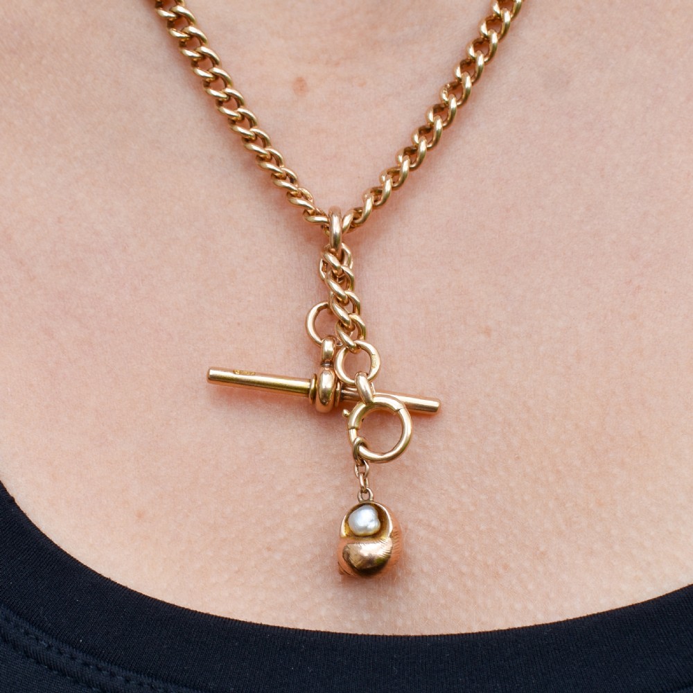 A 9ct yellow gold seashell charm enclosing a single pearl with a top suspension loop. View VIII