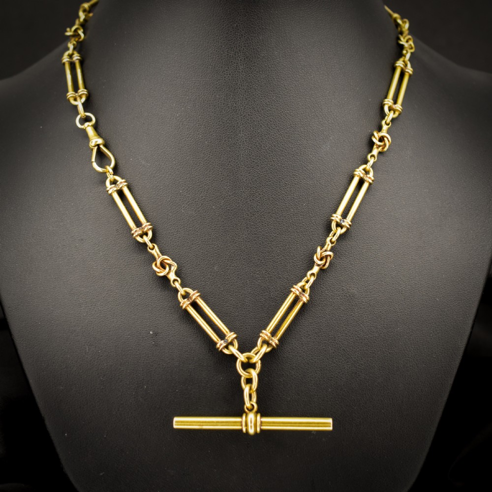 An antique 18ct yellow gold Albert chain necklace displaying alternating trombone links and twisted love knots with a T-bar attachment. View II