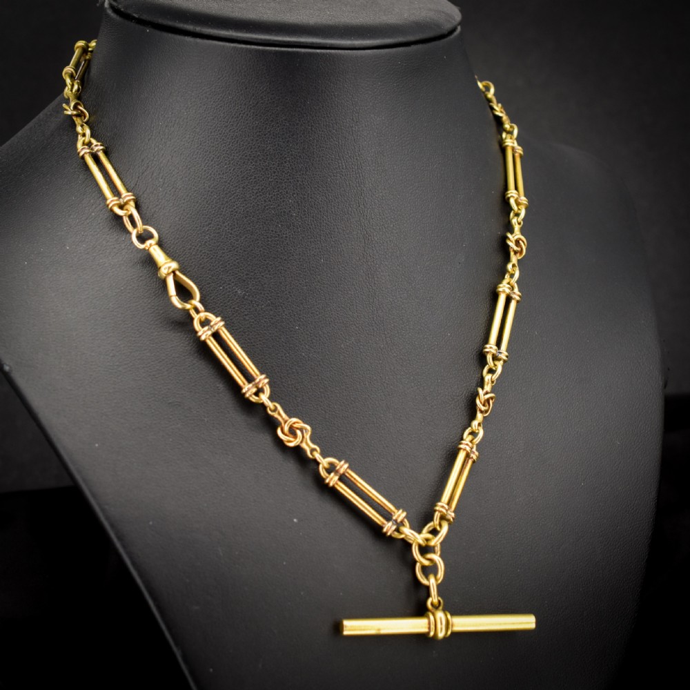 An antique 18ct yellow gold Albert chain necklace displaying alternating trombone links and twisted love knots with a T-bar attachment. View V