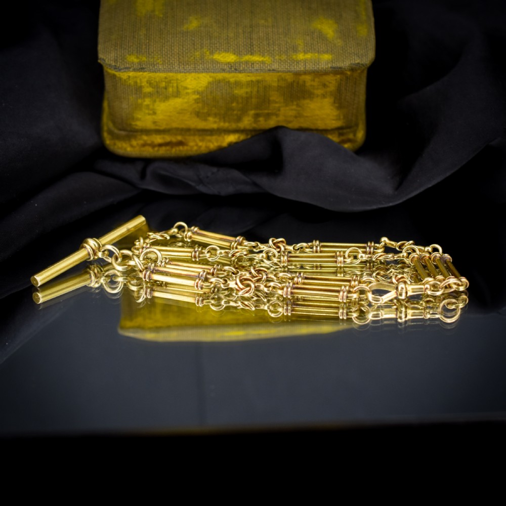 An antique 18ct yellow gold Albert chain necklace displaying alternating trombone links and twisted love knots with a T-bar attachment. View VII