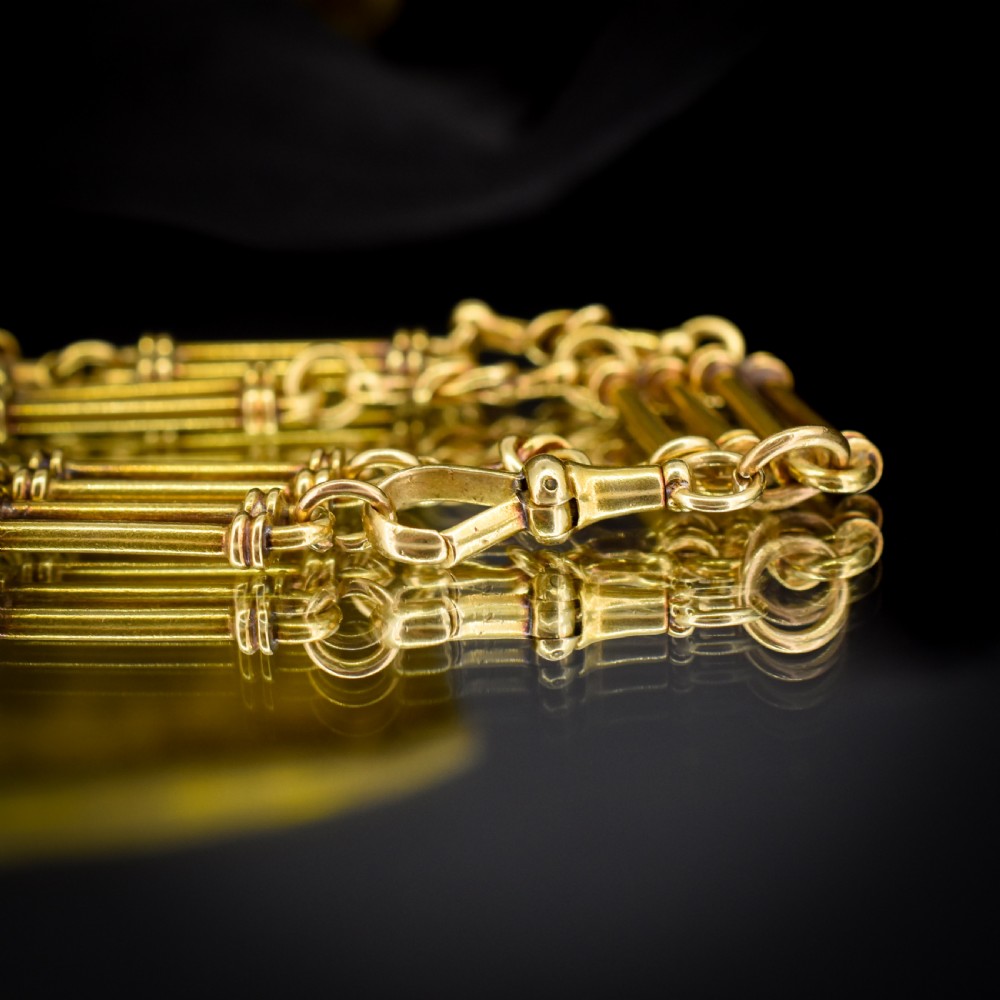An antique 18ct yellow gold Albert chain necklace displaying alternating trombone links and twisted love knots with a T-bar attachment. View VIII