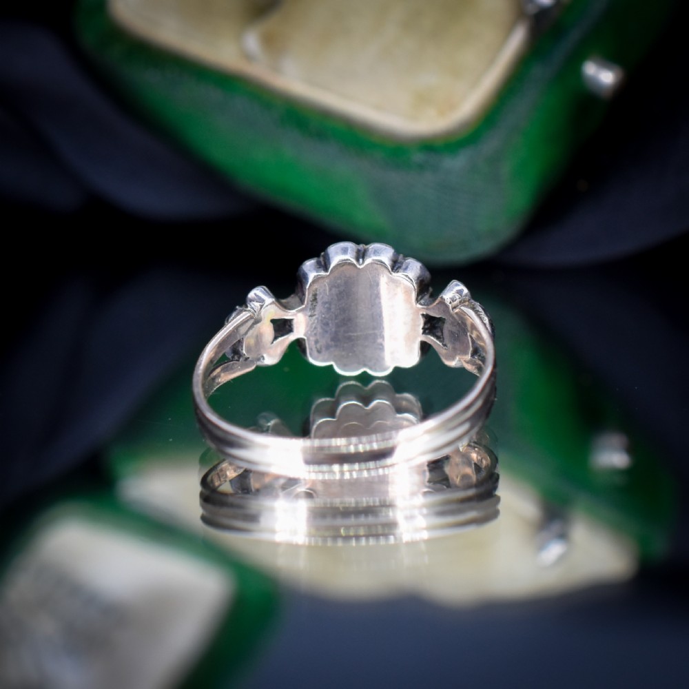 An antique Georgian cluster ring featuring a central cushion-cut green paste stone surrounded by clear paste stones set in silver and gold. View V
