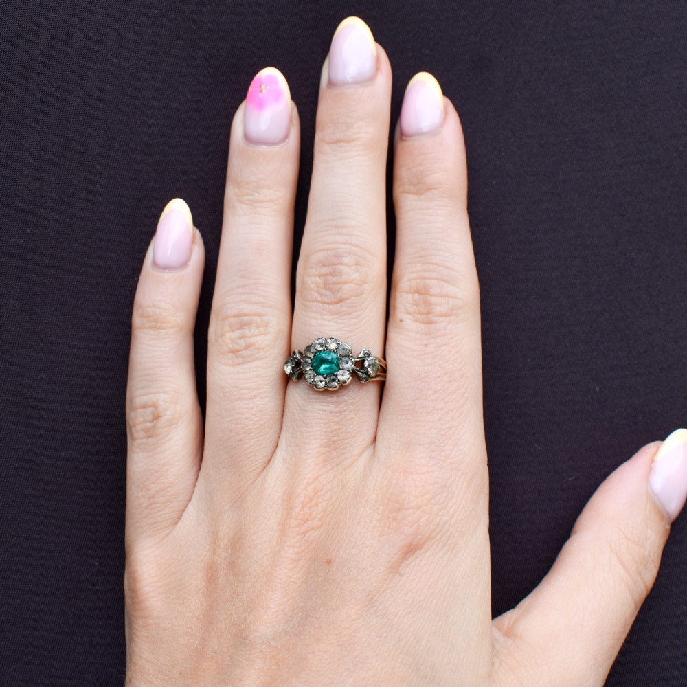 An antique Georgian cluster ring featuring a central cushion-cut green paste stone surrounded by clear paste stones set in silver and gold. View VIII