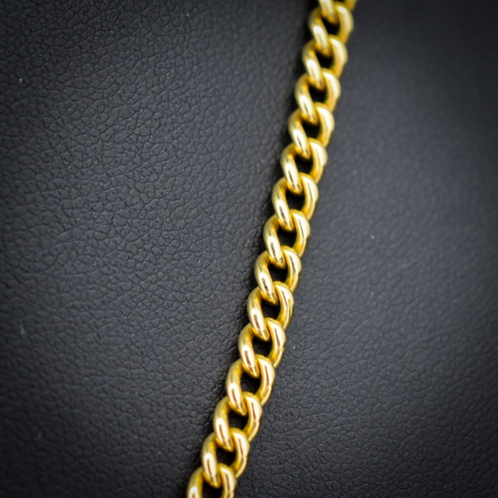 An antique 18ct yellow gold curb link chain necklace featuring a circular bolt ring clasp on a green velvet surface. View IV