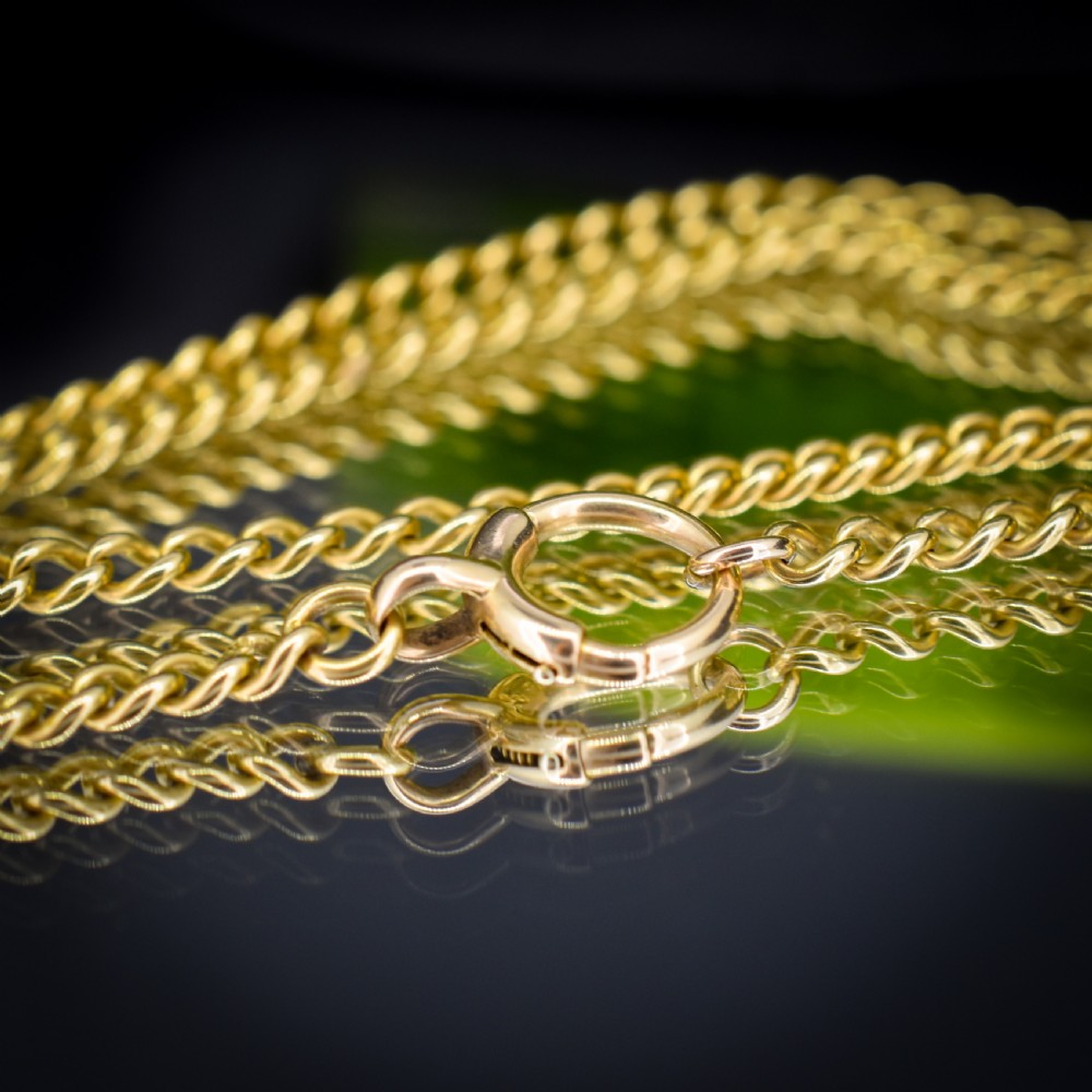 An antique 18ct yellow gold curb link chain necklace featuring a circular bolt ring clasp on a green velvet surface. View VI