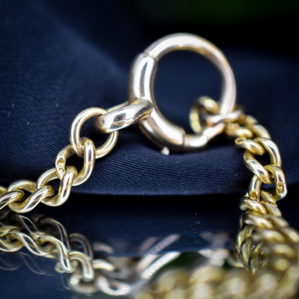 An antique 18ct yellow gold curb link chain necklace featuring a circular bolt ring clasp on a green velvet surface. View VIII