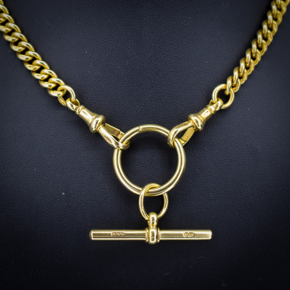 An 18ct yellow gold curb link Albert chain necklace featuring a central ring with a T-bar drop, displayed on a black jewellery bust. View II