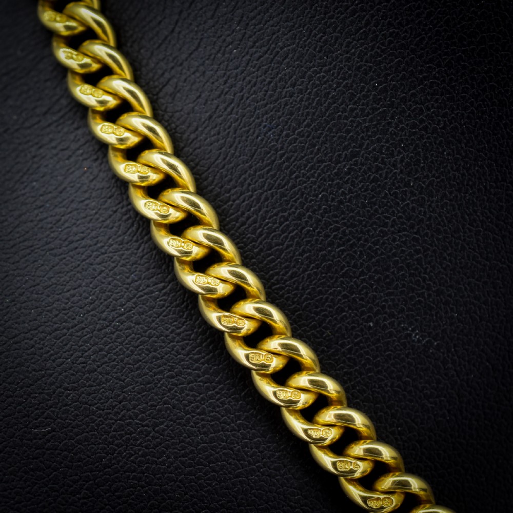 An 18ct yellow gold curb link Albert chain necklace featuring a central ring with a T-bar drop, displayed on a black jewellery bust. View III