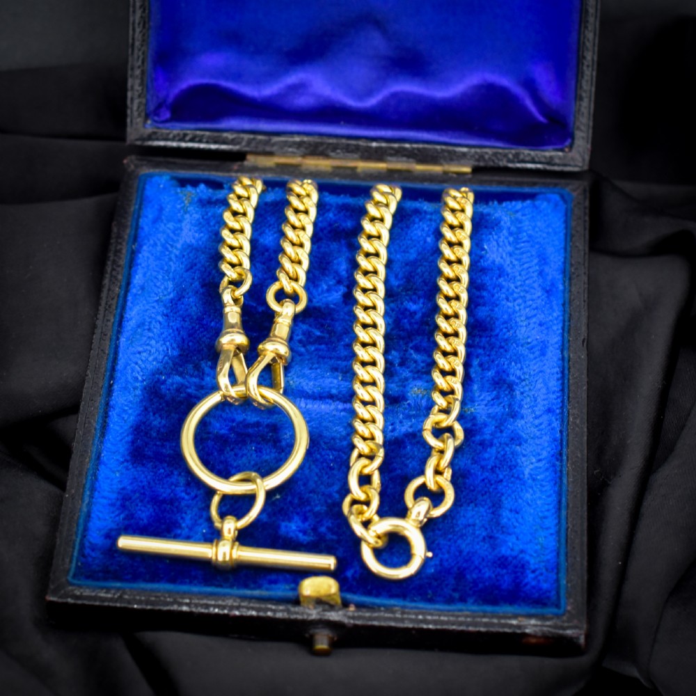 An 18ct yellow gold curb link Albert chain necklace featuring a central ring with a T-bar drop, displayed on a black jewellery bust. View V