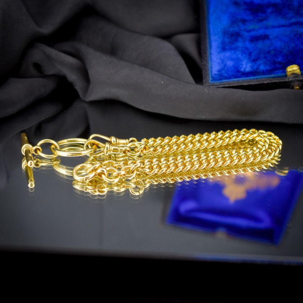 An 18ct yellow gold curb link Albert chain necklace featuring a central ring with a T-bar drop, displayed on a black jewellery bust. View VI