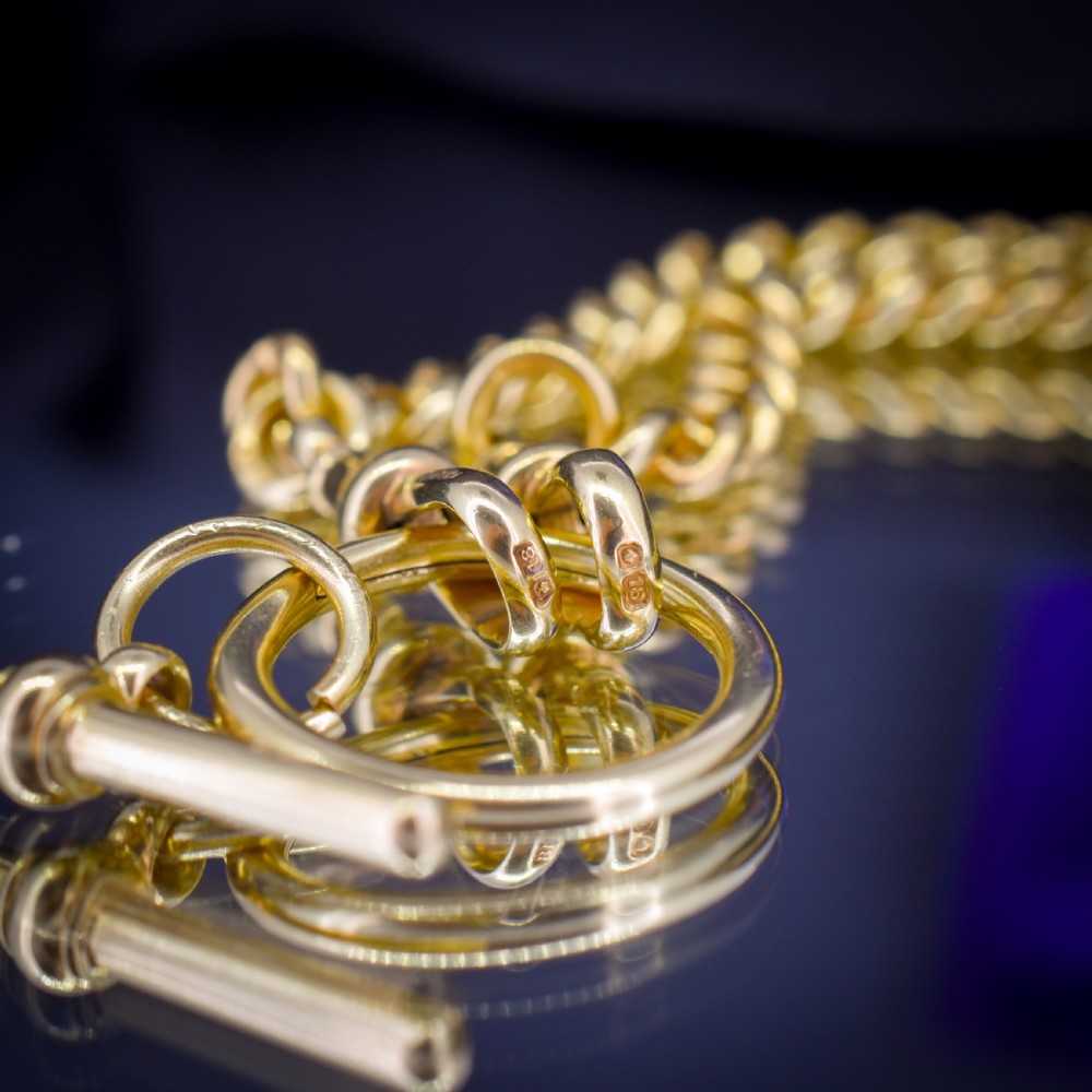 An 18ct yellow gold curb link Albert chain necklace featuring a central ring with a T-bar drop, displayed on a black jewellery bust. View VII