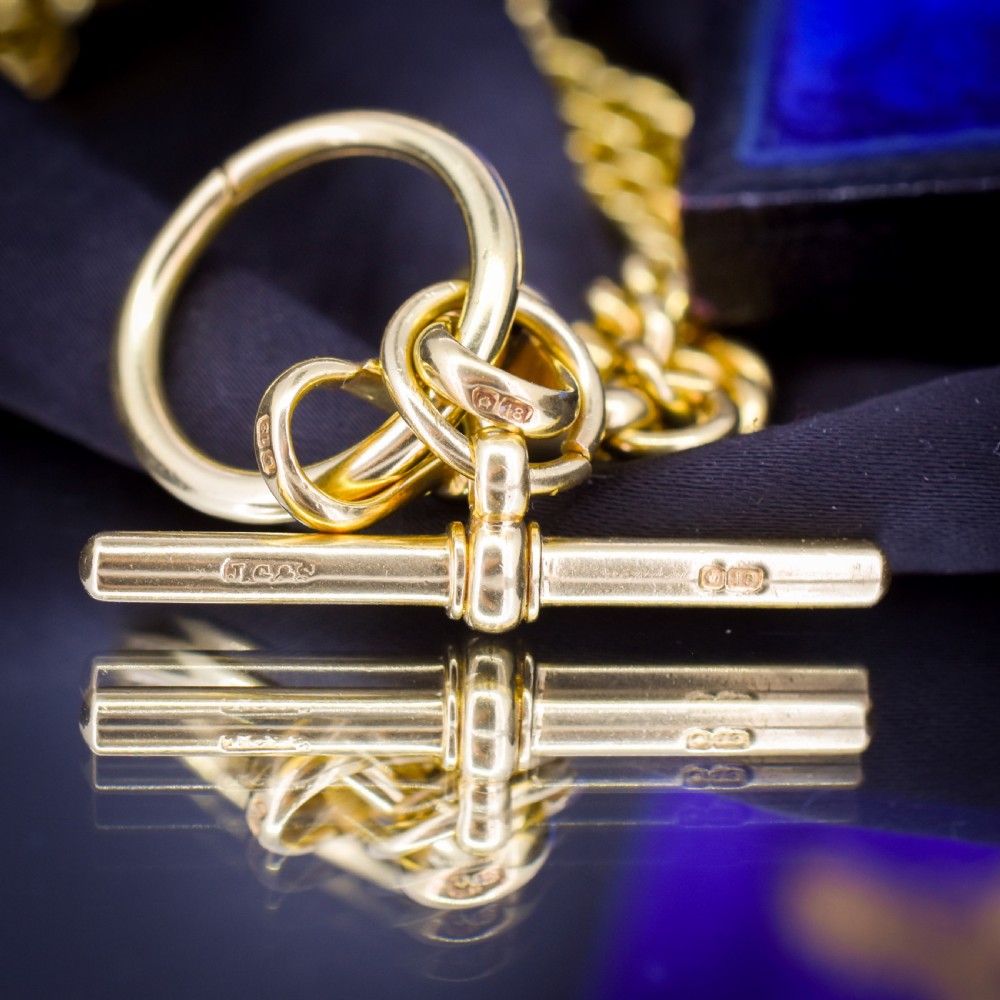 An 18ct yellow gold curb link Albert chain necklace featuring a central ring with a T-bar drop, displayed on a black jewellery bust. View VIII