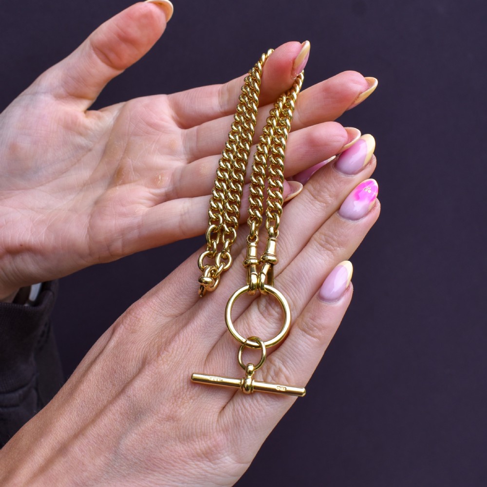 An 18ct yellow gold curb link Albert chain necklace featuring a central ring with a T-bar drop, displayed on a black jewellery bust. View IX