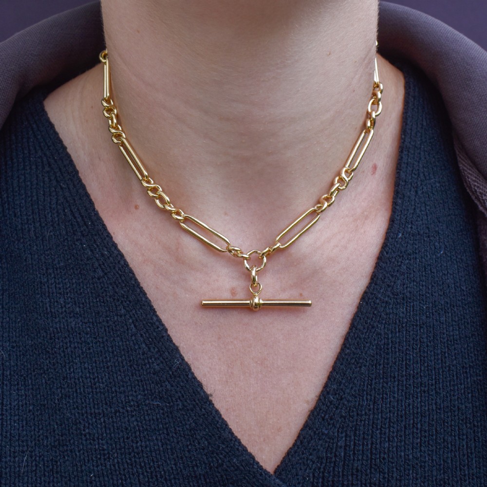 An antique 18ct yellow gold trombone link watch chain featuring an integrated T-bar and swivel clasp fastener. View X