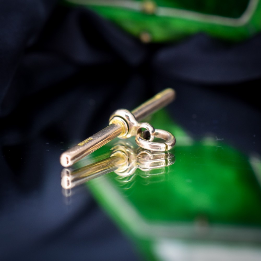 An antique 15ct yellow gold T-bar pendant featuring a smooth crossbar, central jump rings, and stamped British hallmarks. View V