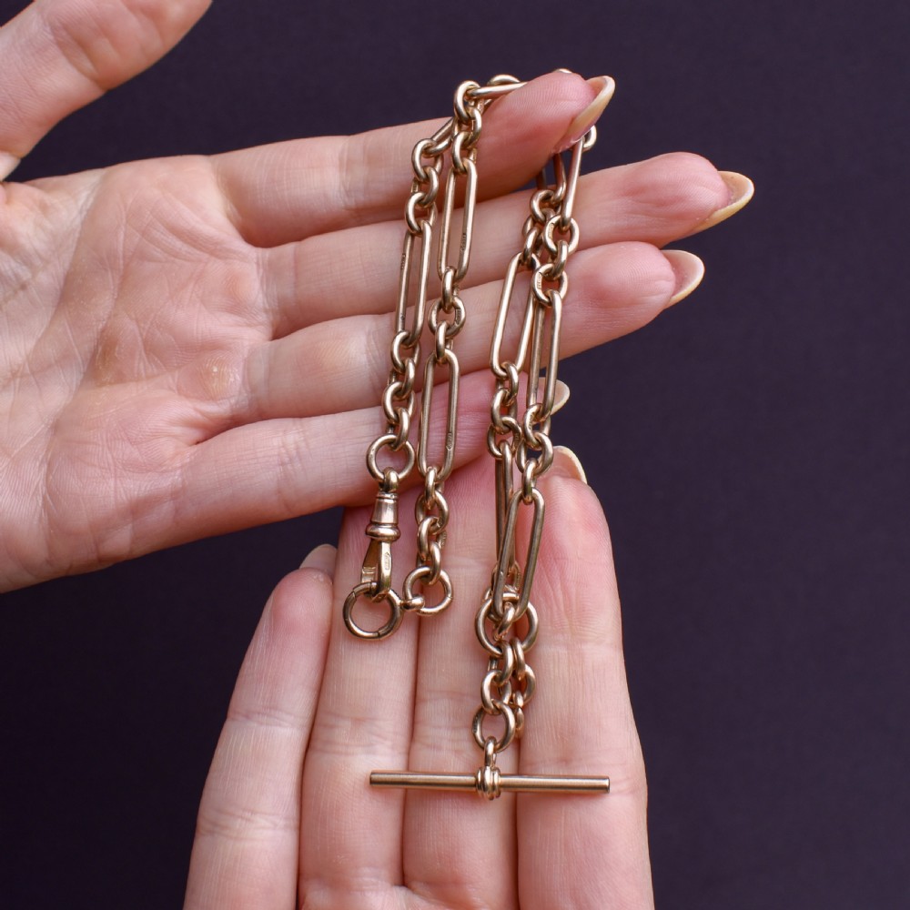 A 9ct yellow gold Art Deco Albert watch chain featuring alternating elongated trombone links, a swivel clasp, and a T-bar.