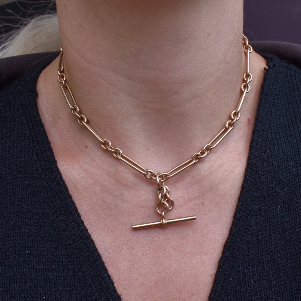 A 9ct yellow gold Art Deco Albert watch chain featuring alternating elongated trombone links, a swivel clasp, and a T-bar. View II