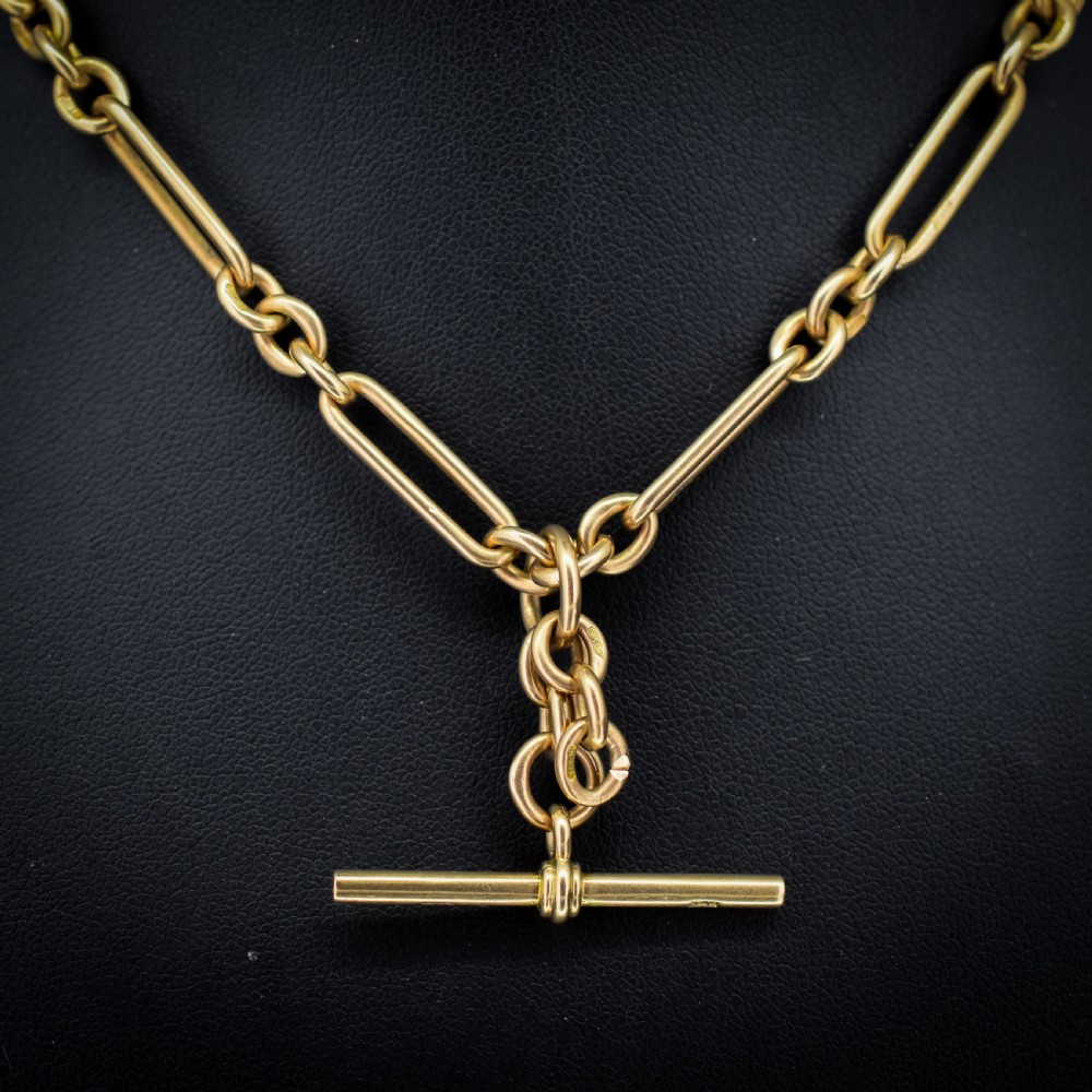 A 9ct yellow gold Art Deco Albert watch chain featuring alternating elongated trombone links, a swivel clasp, and a T-bar. View IV