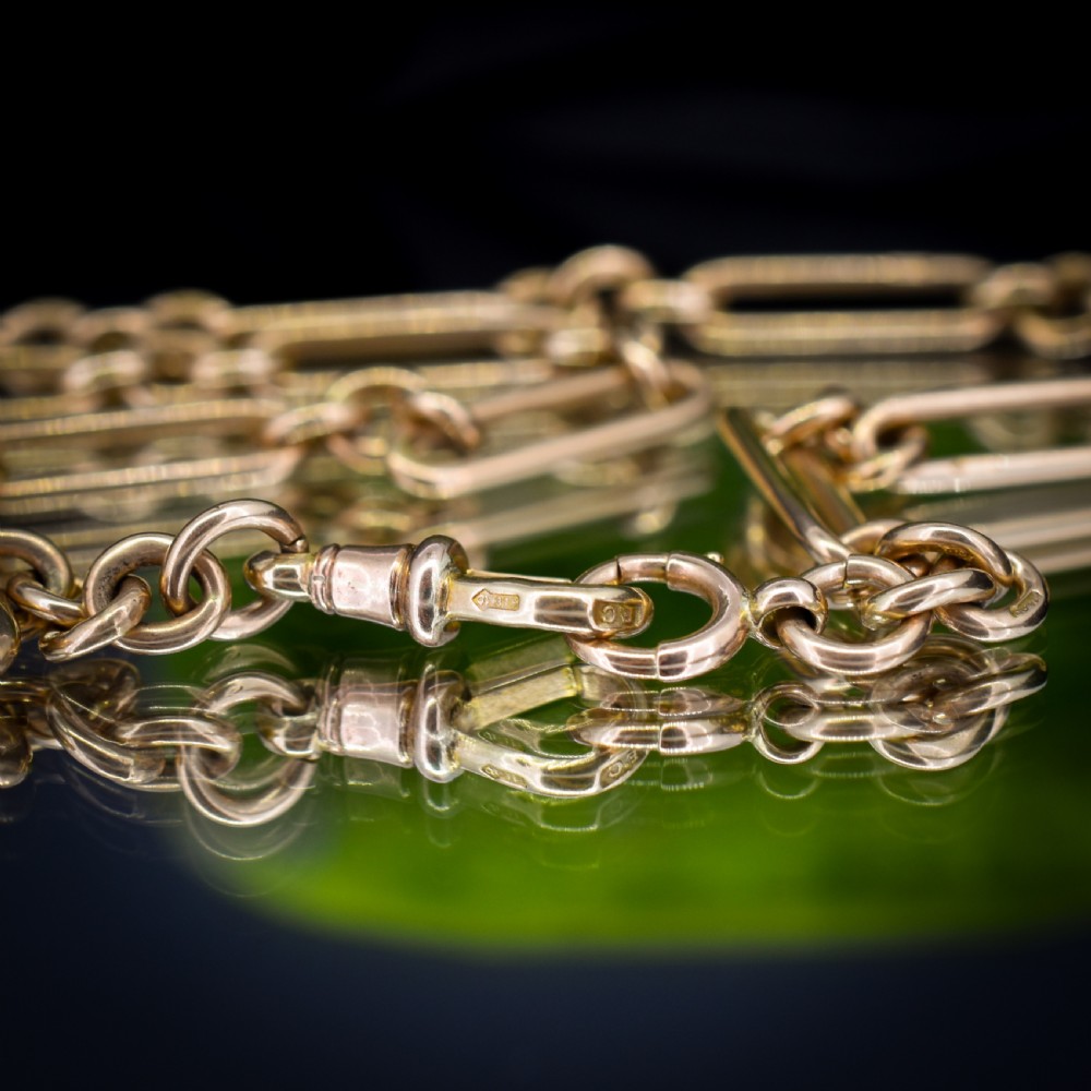A 9ct yellow gold Art Deco Albert watch chain featuring alternating elongated trombone links, a swivel clasp, and a T-bar. View VIII
