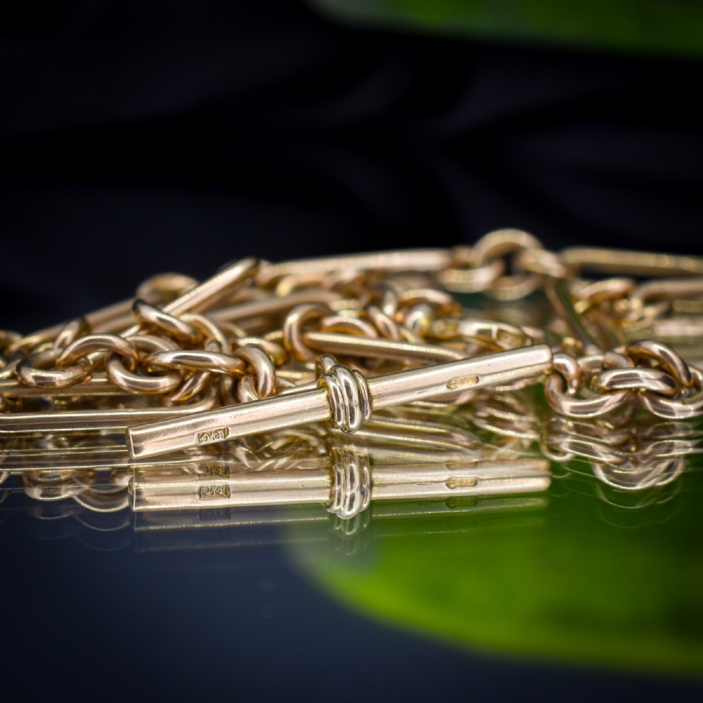 A 9ct yellow gold Art Deco Albert watch chain featuring alternating elongated trombone links, a swivel clasp, and a T-bar. View IX