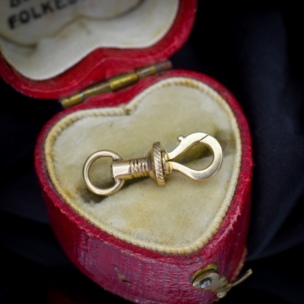 An antique 12ct yellow gold dog clip fastener with a textured screw collar mechanism and top swivel ring.