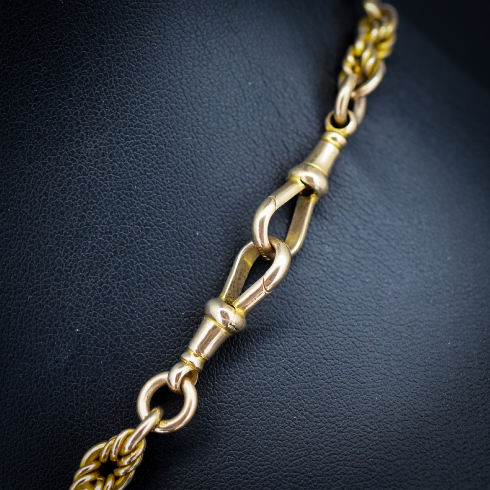 A 9ct yellow gold Albert chain featuring alternating elongated trombone links and textured love knot links with a T-bar and swivel clasp. View VI