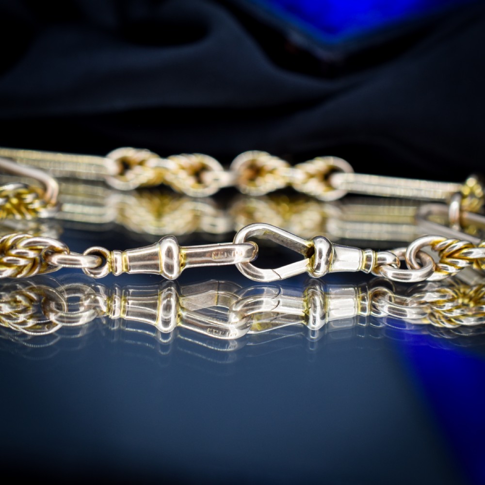 A 9ct yellow gold Albert chain featuring alternating elongated trombone links and textured love knot links with a T-bar and swivel clasp. View VIII