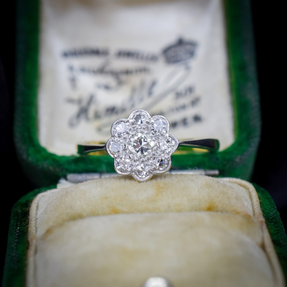 An antique diamond cluster ring arranged in a floral daisy pattern, set in platinum with an 18ct yellow gold band.