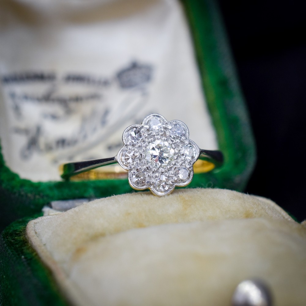 An antique diamond cluster ring arranged in a floral daisy pattern, set in platinum with an 18ct yellow gold band. View II