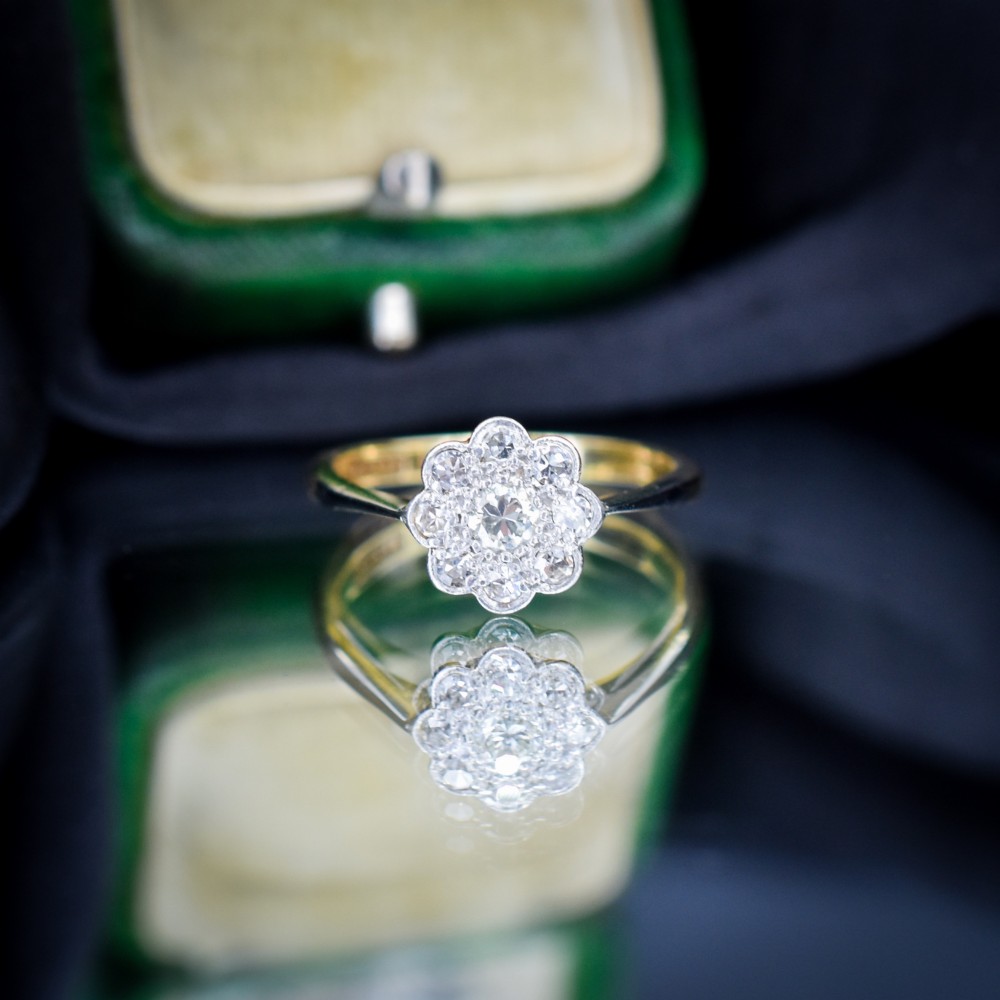An antique diamond cluster ring arranged in a floral daisy pattern, set in platinum with an 18ct yellow gold band. View IV