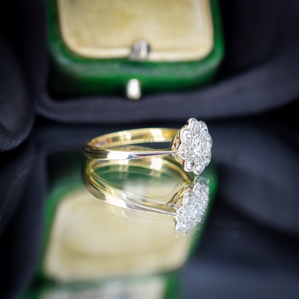 An antique diamond cluster ring arranged in a floral daisy pattern, set in platinum with an 18ct yellow gold band. View V