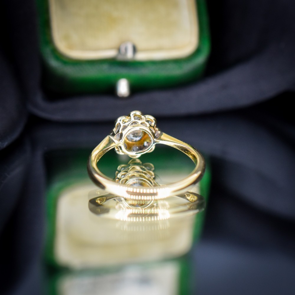 An antique diamond cluster ring arranged in a floral daisy pattern, set in platinum with an 18ct yellow gold band. View VI