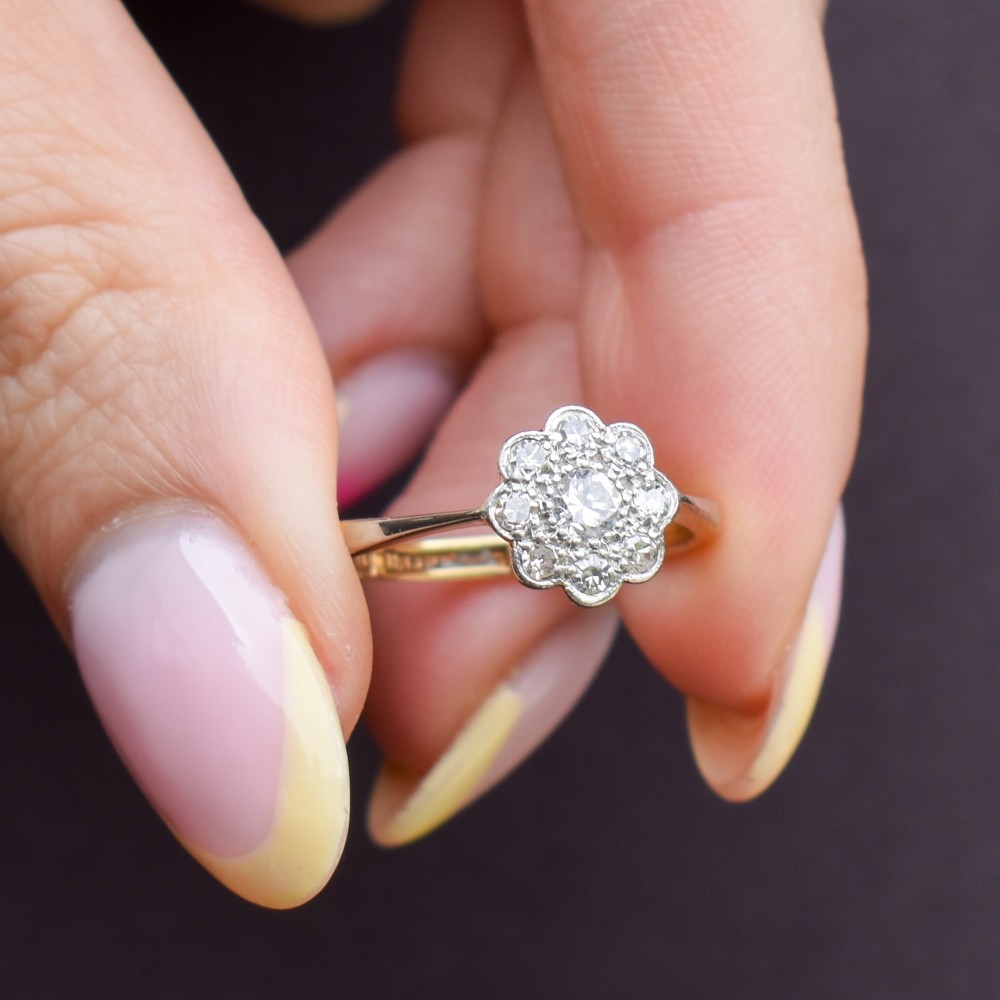 An antique diamond cluster ring arranged in a floral daisy pattern, set in platinum with an 18ct yellow gold band. View IX