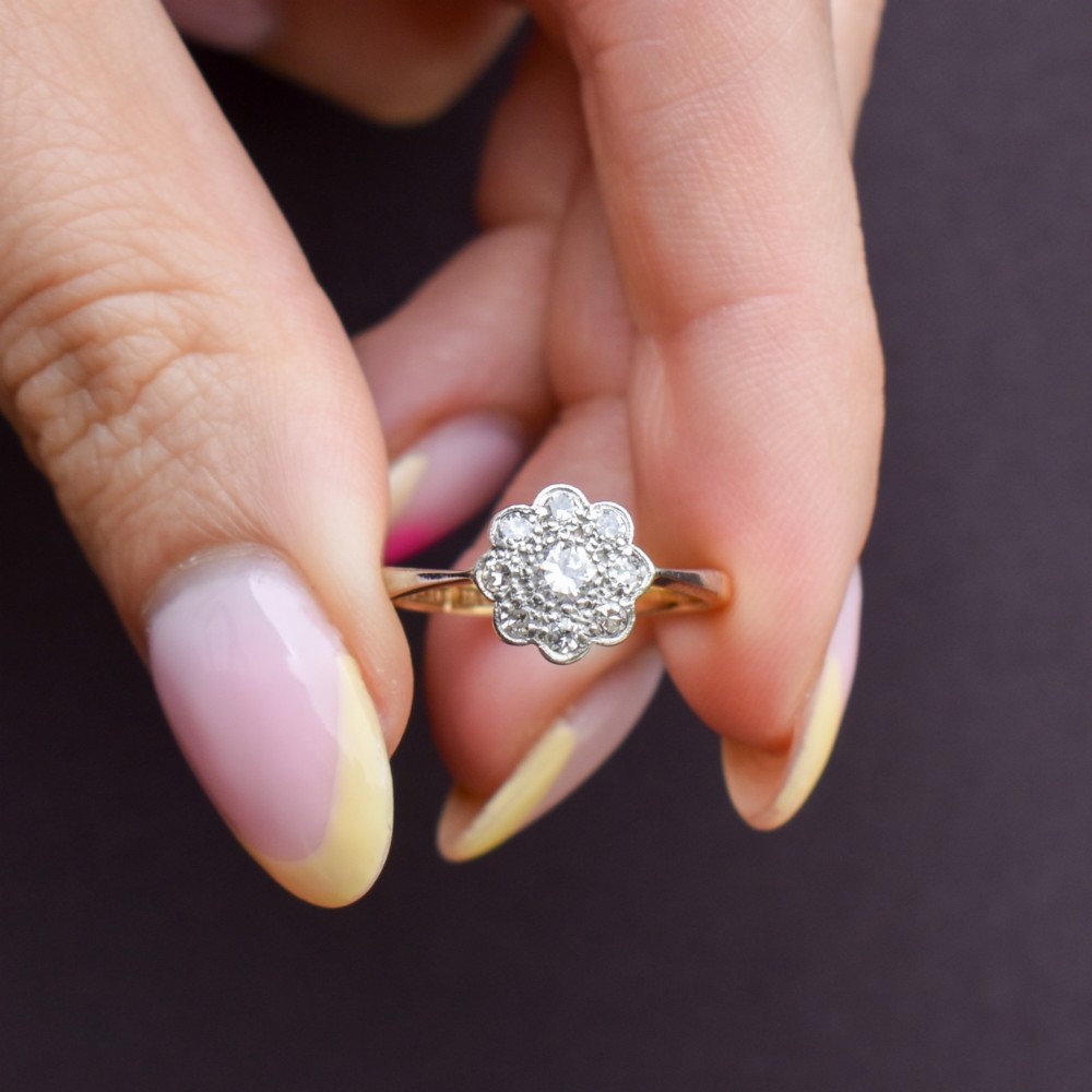 An antique diamond cluster ring arranged in a floral daisy pattern, set in platinum with an 18ct yellow gold band. View X