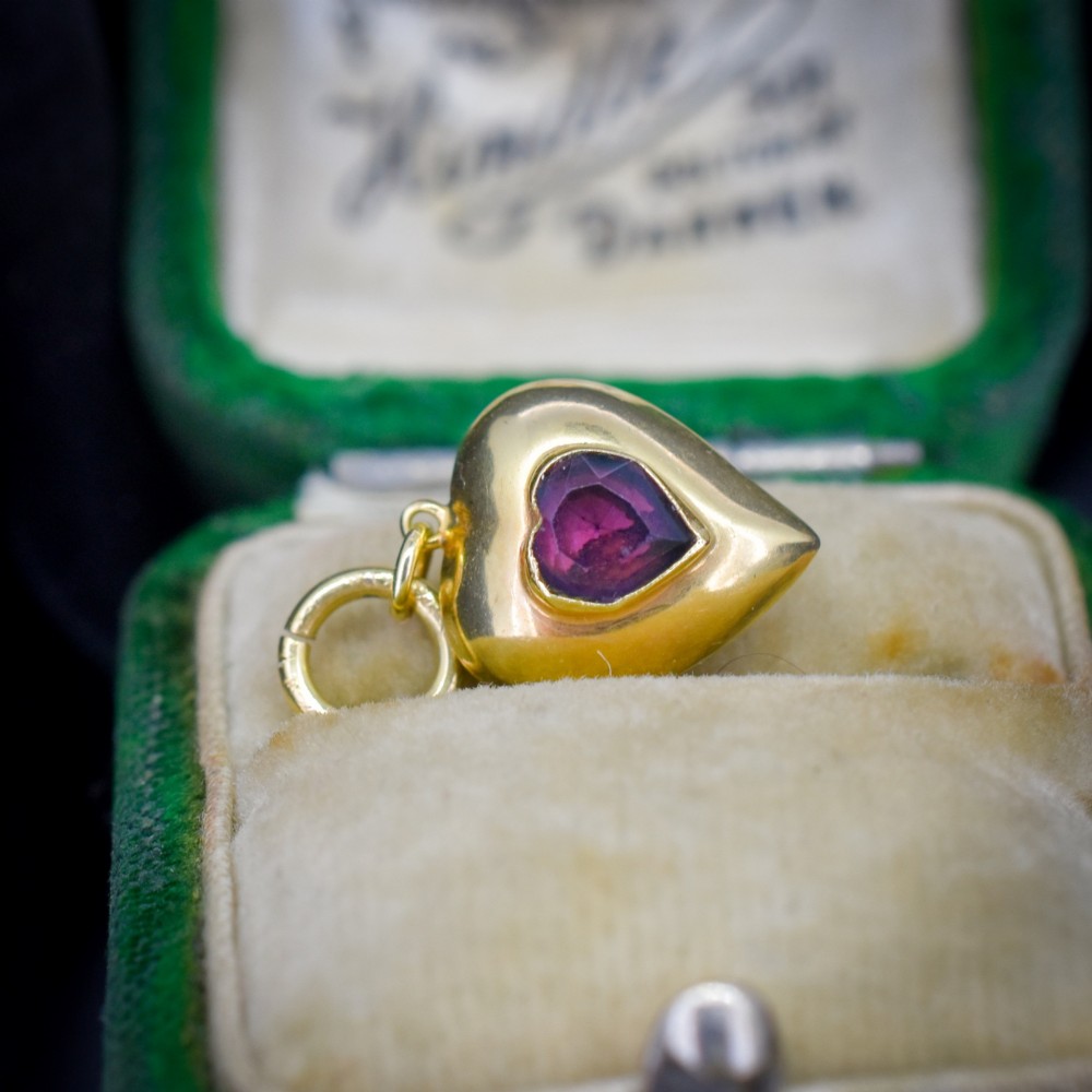 An antique yellow gold puffy heart-shaped charm featuring a central heart-cut purple amethyst paste gem. View III