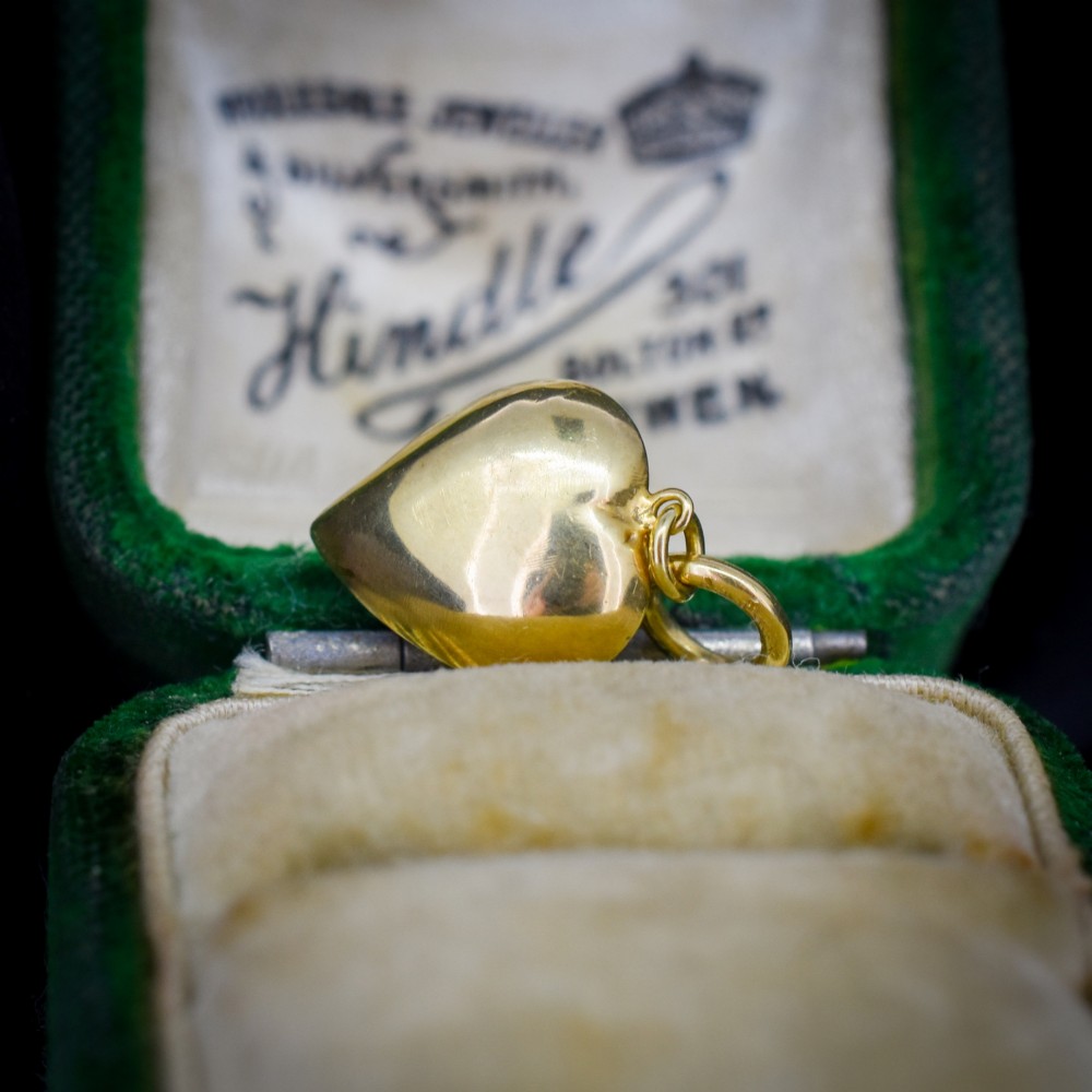 An antique yellow gold puffy heart-shaped charm featuring a central heart-cut purple amethyst paste gem. View IV