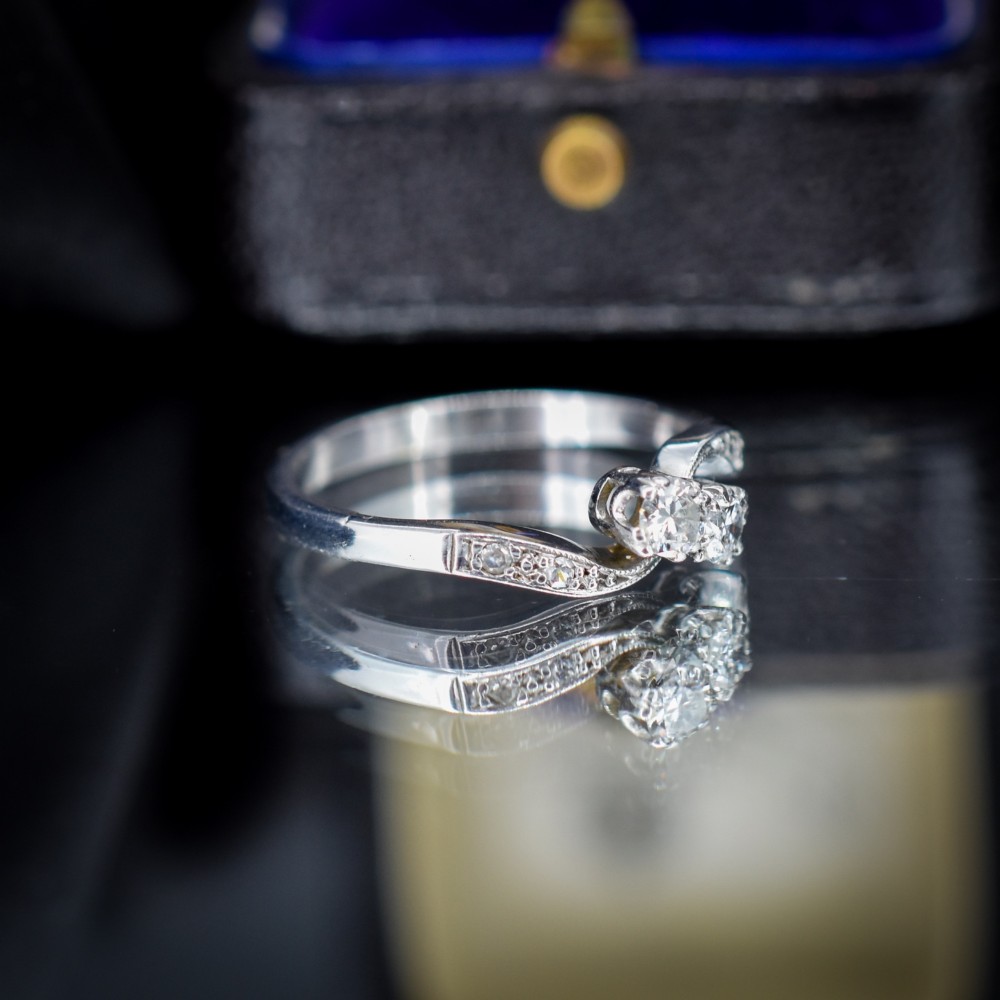 An antique 18ct white gold Toi et Moi ring featuring two central round diamonds set in a diagonal twist arrangement with diamond-set shoulders. View IV