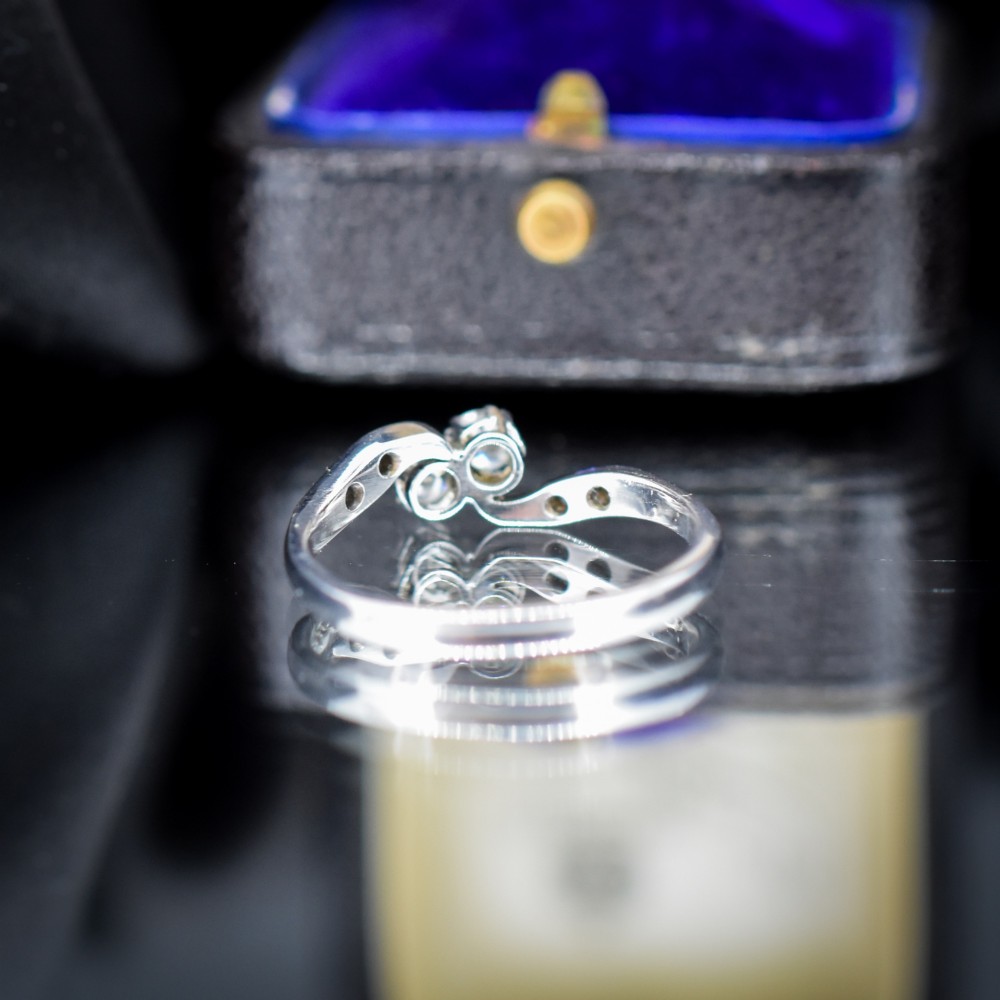 An antique 18ct white gold Toi et Moi ring featuring two central round diamonds set in a diagonal twist arrangement with diamond-set shoulders. View V